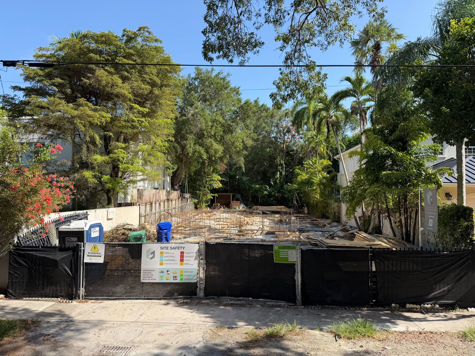 Española — the site from the street, behind the safety fence, July 2026